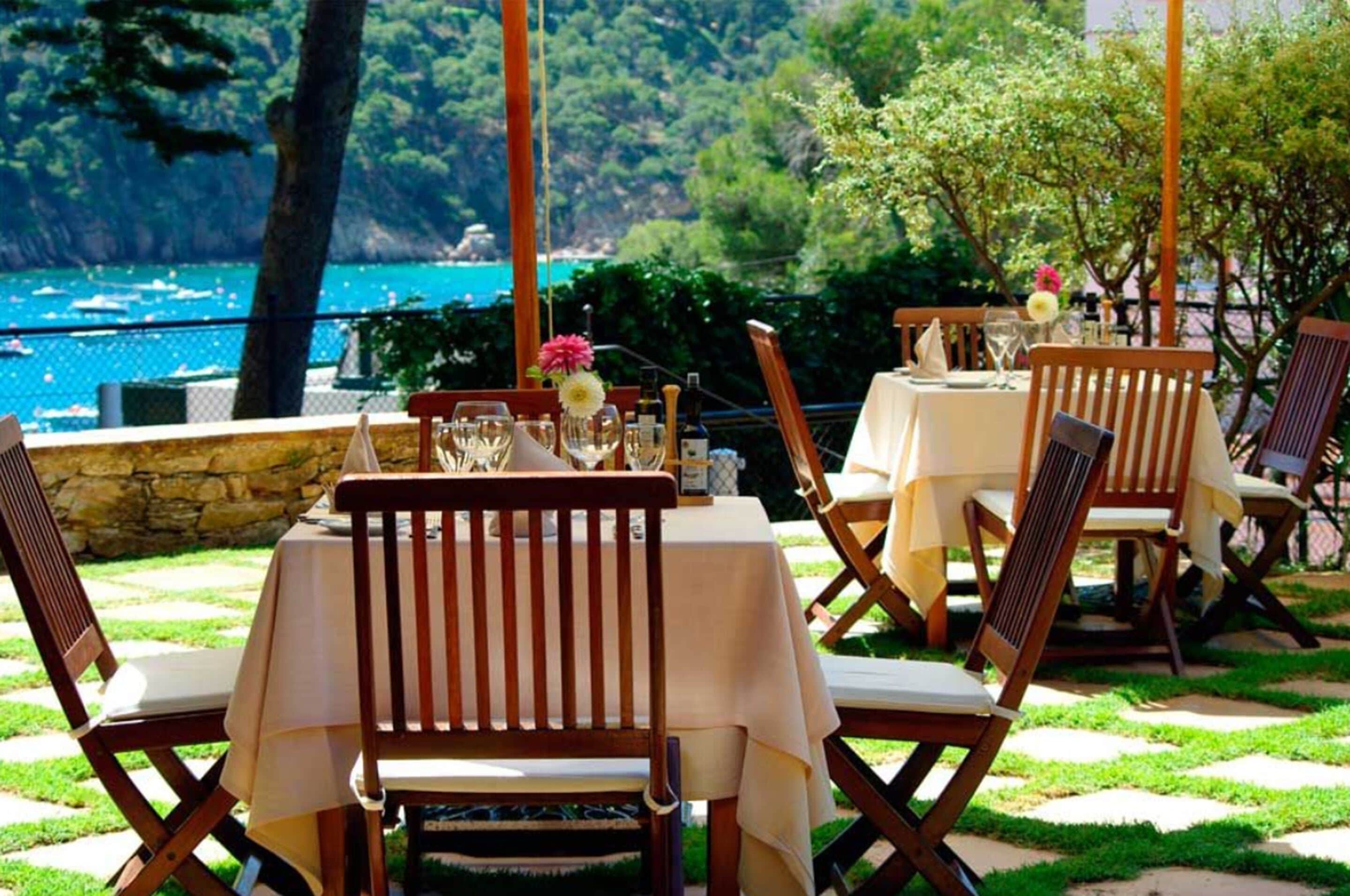 An outdoor dining area with tables and chairs, overlooking a scenic coastal view.