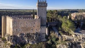 A historic castle with a prominent tower, surrounded by natural landscape and additional buildings. - Parador de Alarcón (Alarcon)