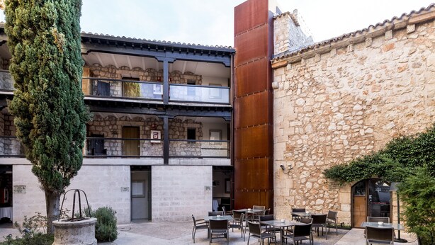 A courtyard with outdoor seating, stone walls, and a tree. - Parador de Alarcón (Alarcon)