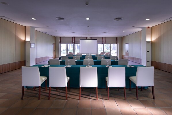 A conference room with a long table, white chairs, and a large screen. - Parador de Benicarló (Benicarlo)