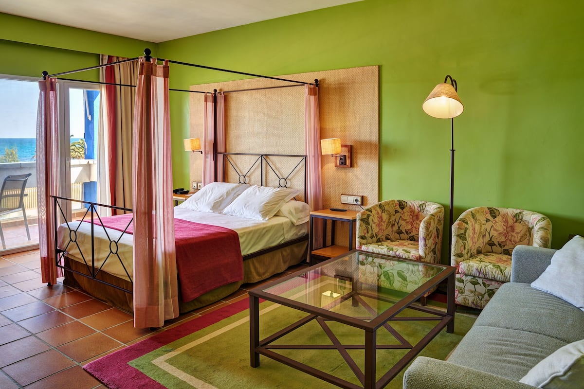 Een kamer met een hemelbed, een bank, een stoel, een tafel en een lamp.