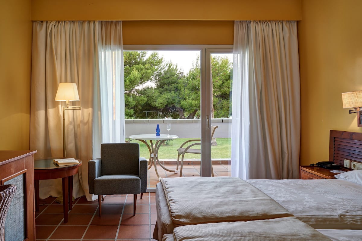 Een hotelkamer met een bed, een stoel, een tafel met een lamp en uitzicht op de omgeving.