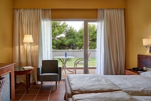 A hotel room with a bed, a chair, a table with a lamp, and a view of the outdoors. - Parador de Benicarló (Benicarlo)