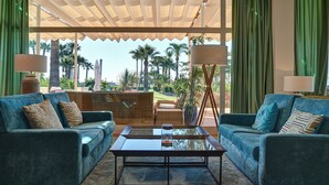 Sala de estar con dos sofás, una mesa de centro y vistas a palmeras y una piscina.