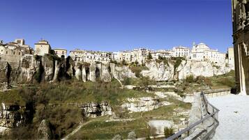 Un pueblo histórico con edificios encaramados a acantilados rocosos, cielo despejado y un camino que conduce a los edificios.