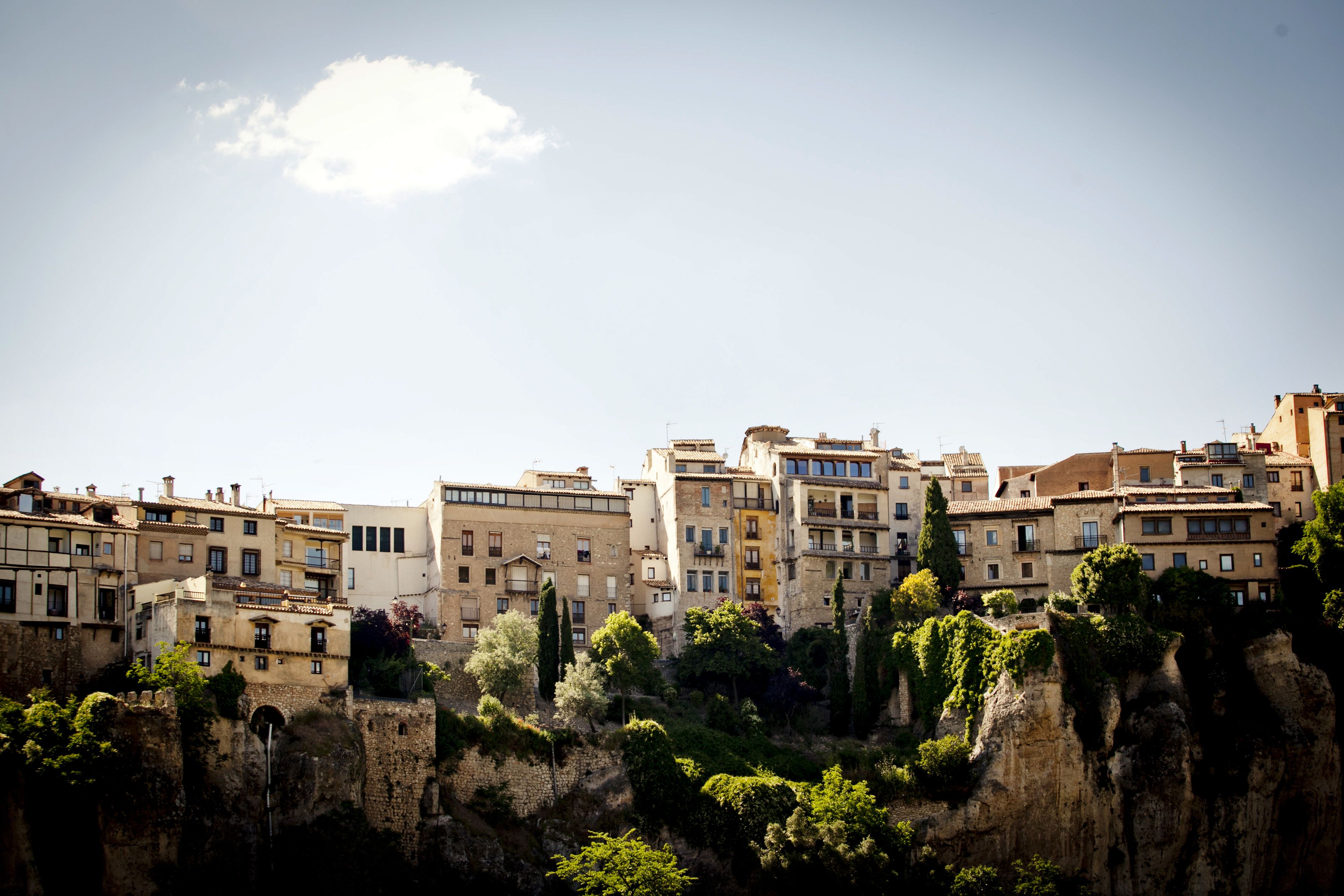Un pueblo histórico con edificios de varios pisos, algunos con balcones, y un imponente acantilado en primer plano.