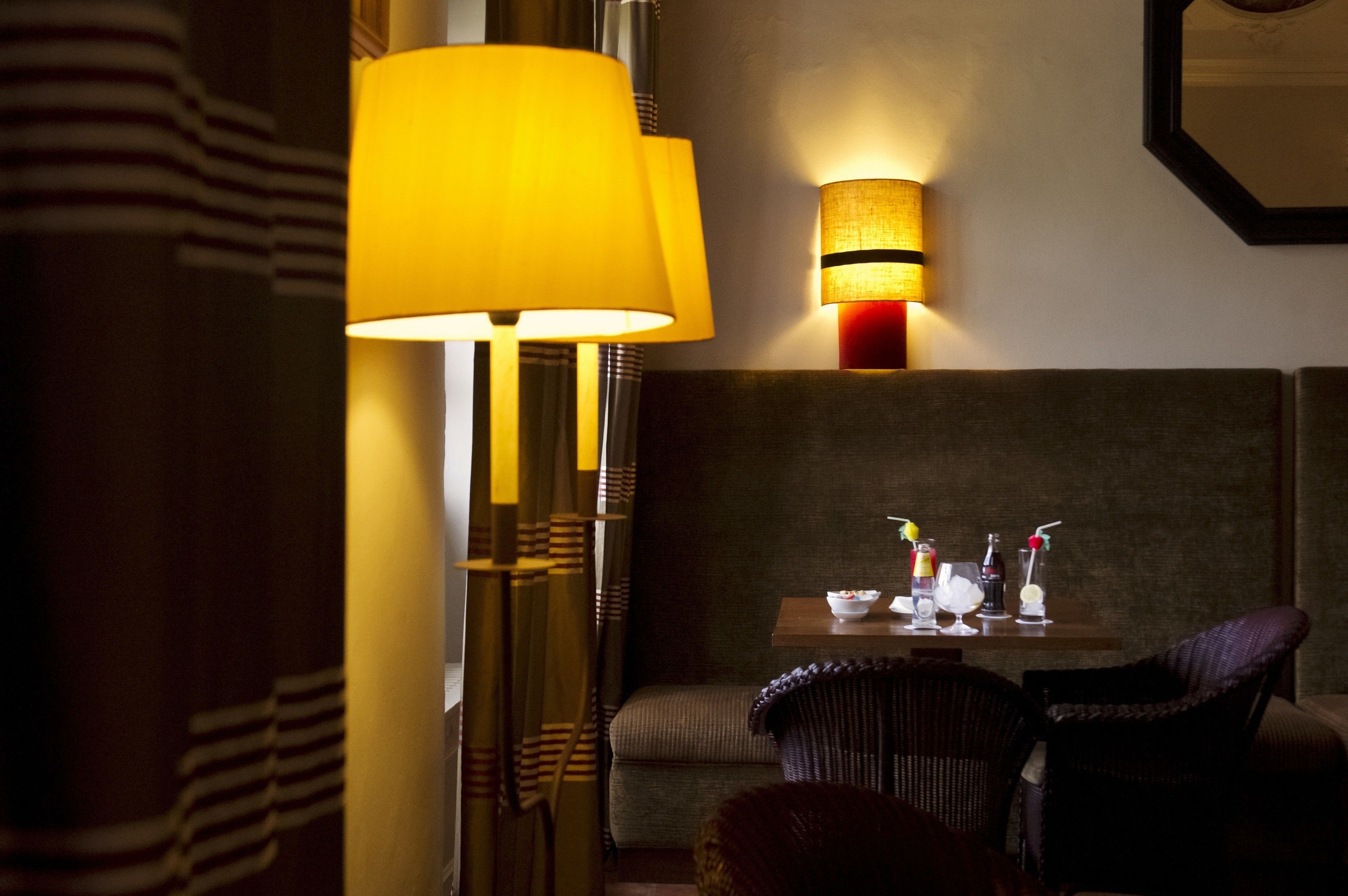 Une pièce chaleureuse avec un canapé, une table avec des boissons et une lampe fixée au mur.