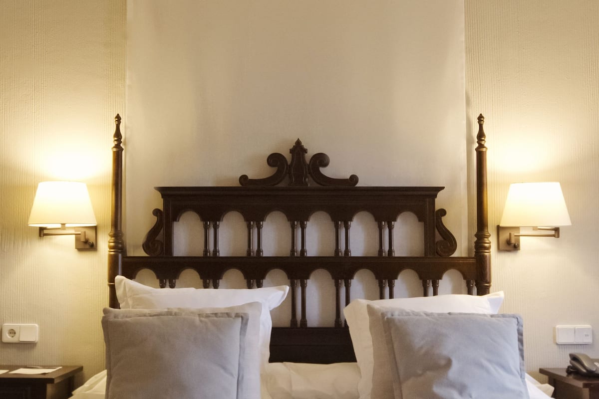 A hotel room with a large bed, two bedside lamps, and a wooden headboard.