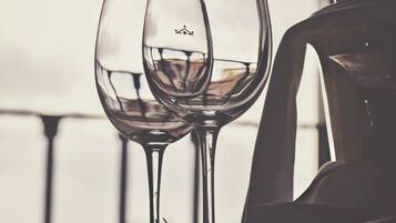 Two wine glasses on a table with a bottle of wine and a chair in the background.