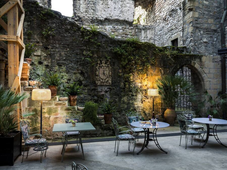 An outdoor patio with stone walls, metal furniture, and potted plants.