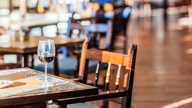 A restaurant interior with tables, chairs, and a glass of red wine on a table. - Parador de Manzanares (Manzanares)