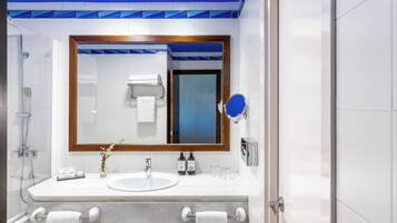 A modern bathroom with a large mirror, white tiles, a shower, and a vanity with a sink and towel rack.