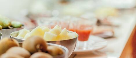 Un bufé de desayuno con diversas frutas y bebidas.