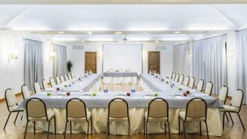 Un salón de conferencias con una larga mesa, sillas y una pizarra.