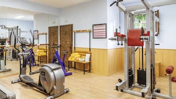 Une salle de sport équipée de machines de cardio, de matériel de musculation et d’un miroir mural.