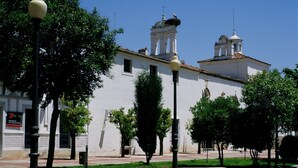 A courtyard with a fountain, a lamp post, and a building with a bell tower.