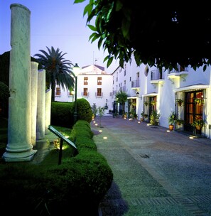 A courtyard with white buildings, columns, and potted plants.