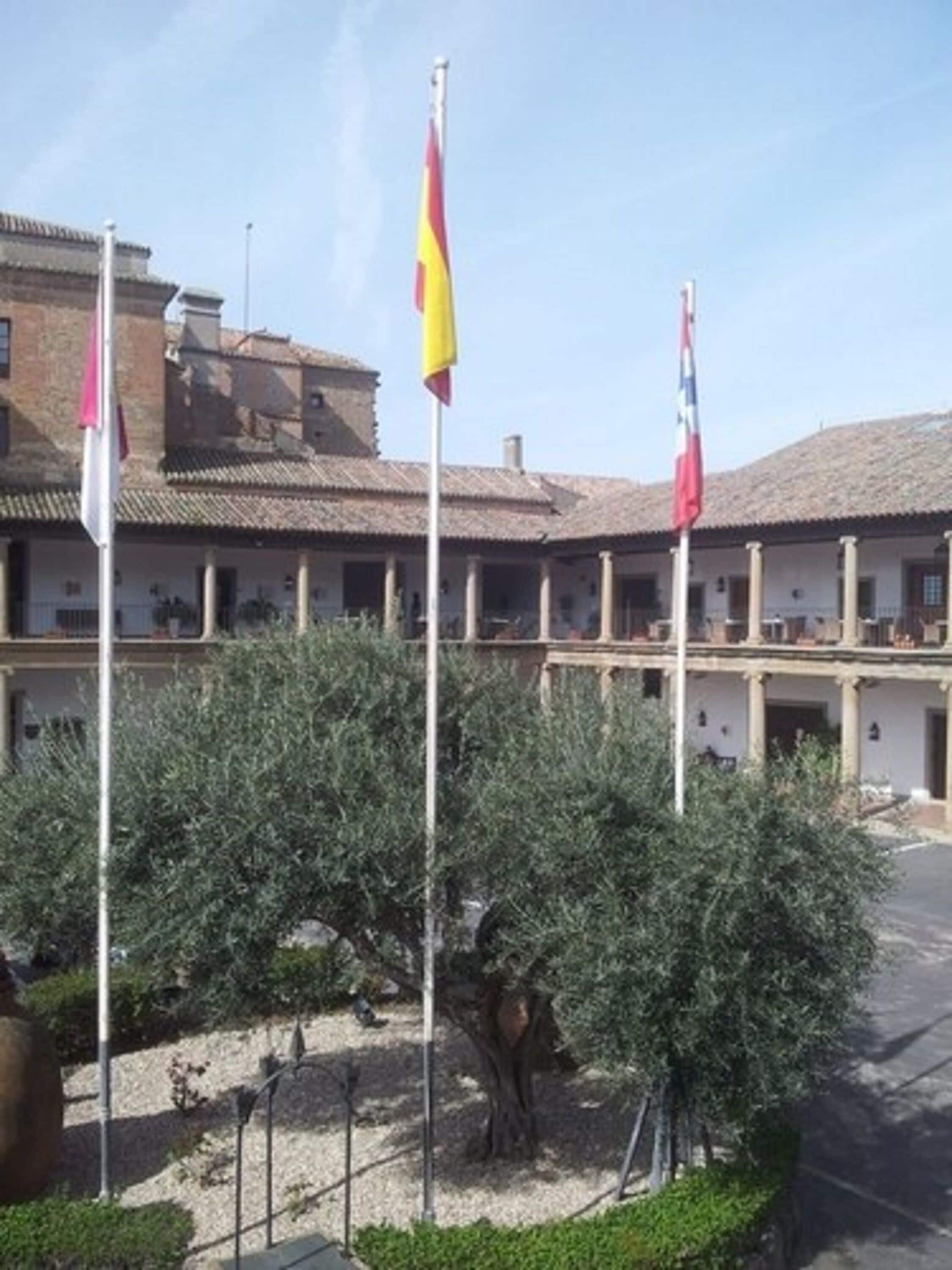Un edificio con patio, columnas y banderas.