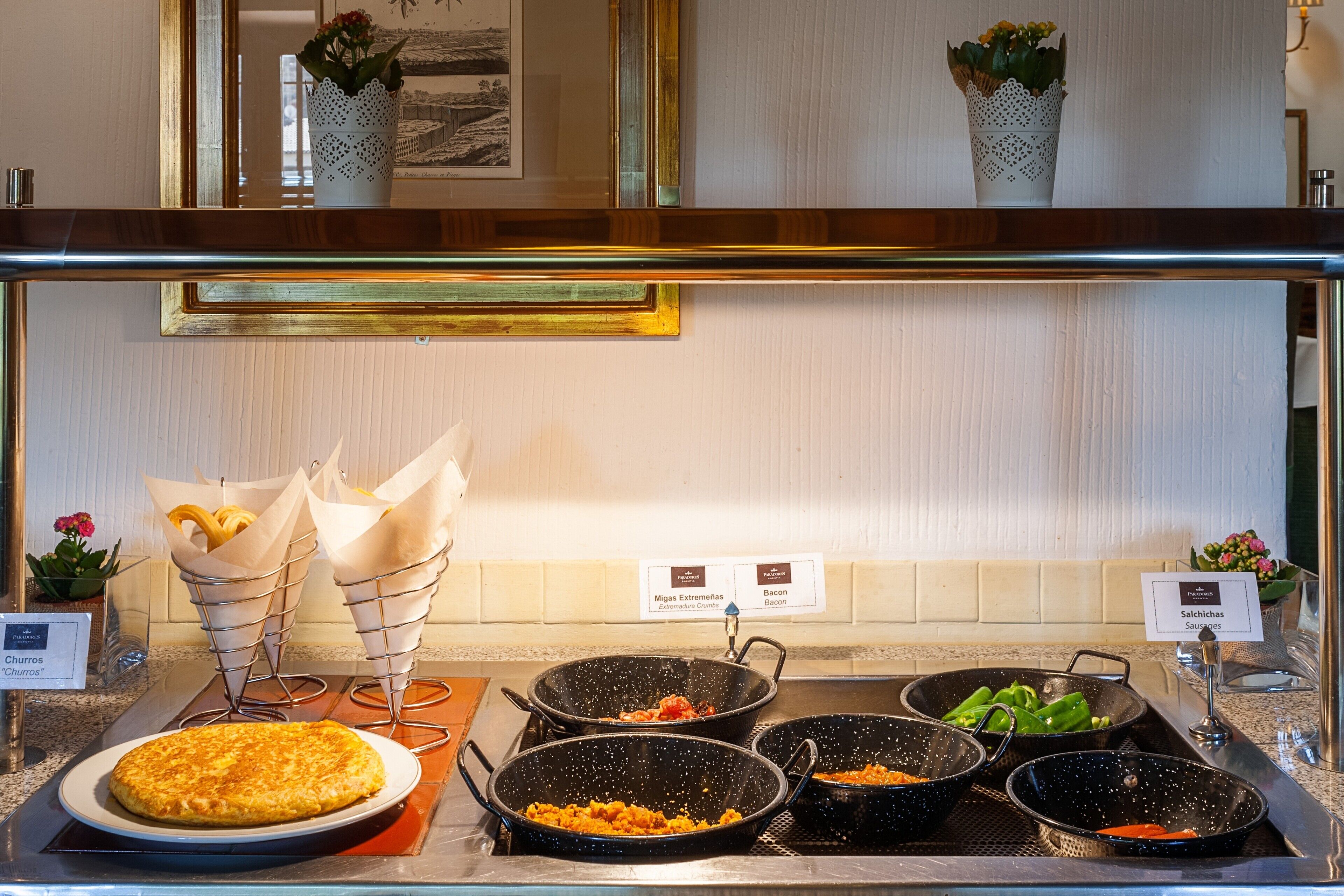 Buffet com diversos pratos, incluindo omeletes, chouriços, bacon e linguiças.
