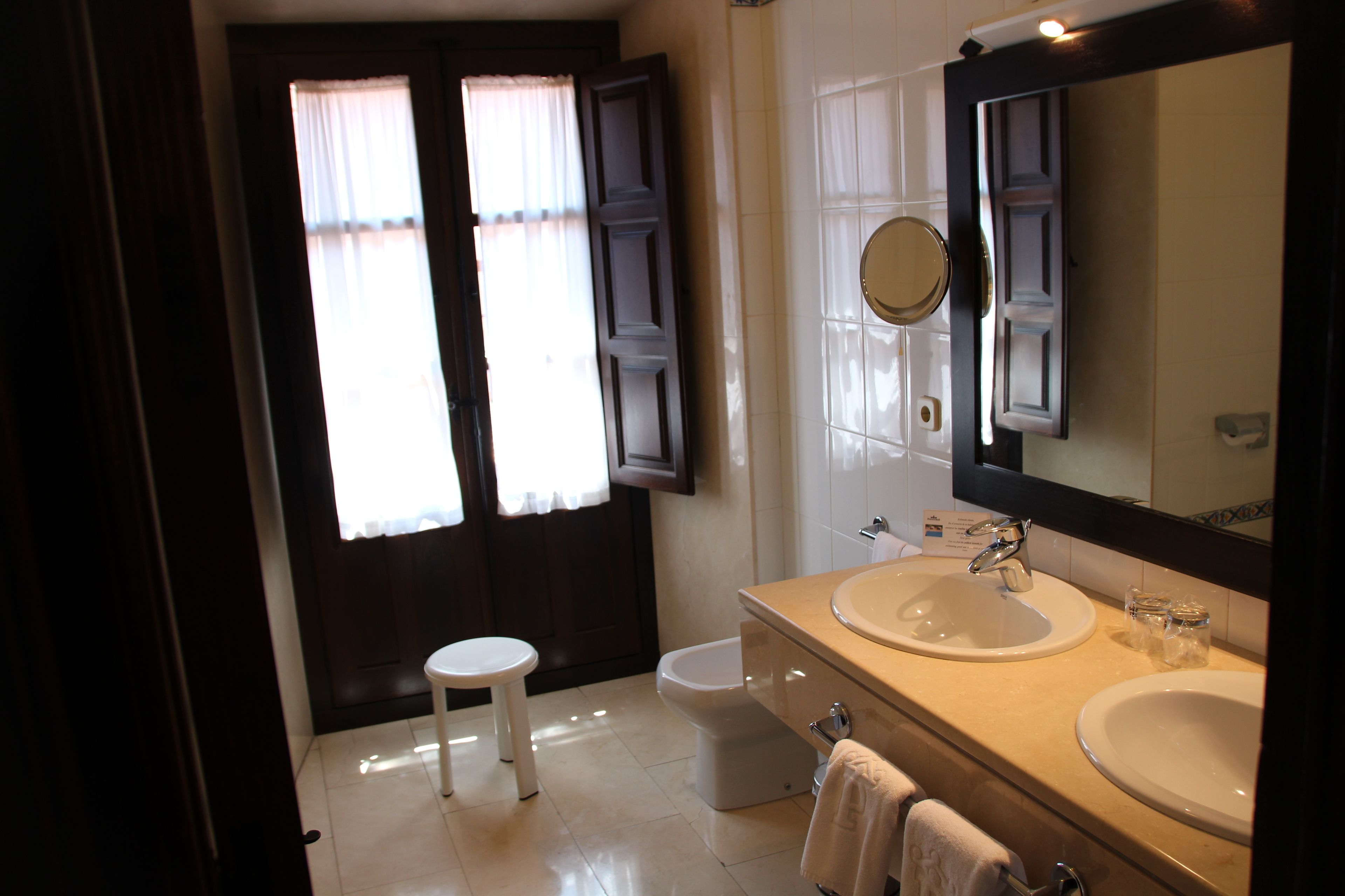 Un baño con dos lavamanos, un inodoro y un espejo.
