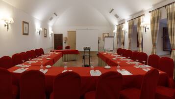 Un salón de conferencias con una larga mesa, sillas rojas y una pizarra.