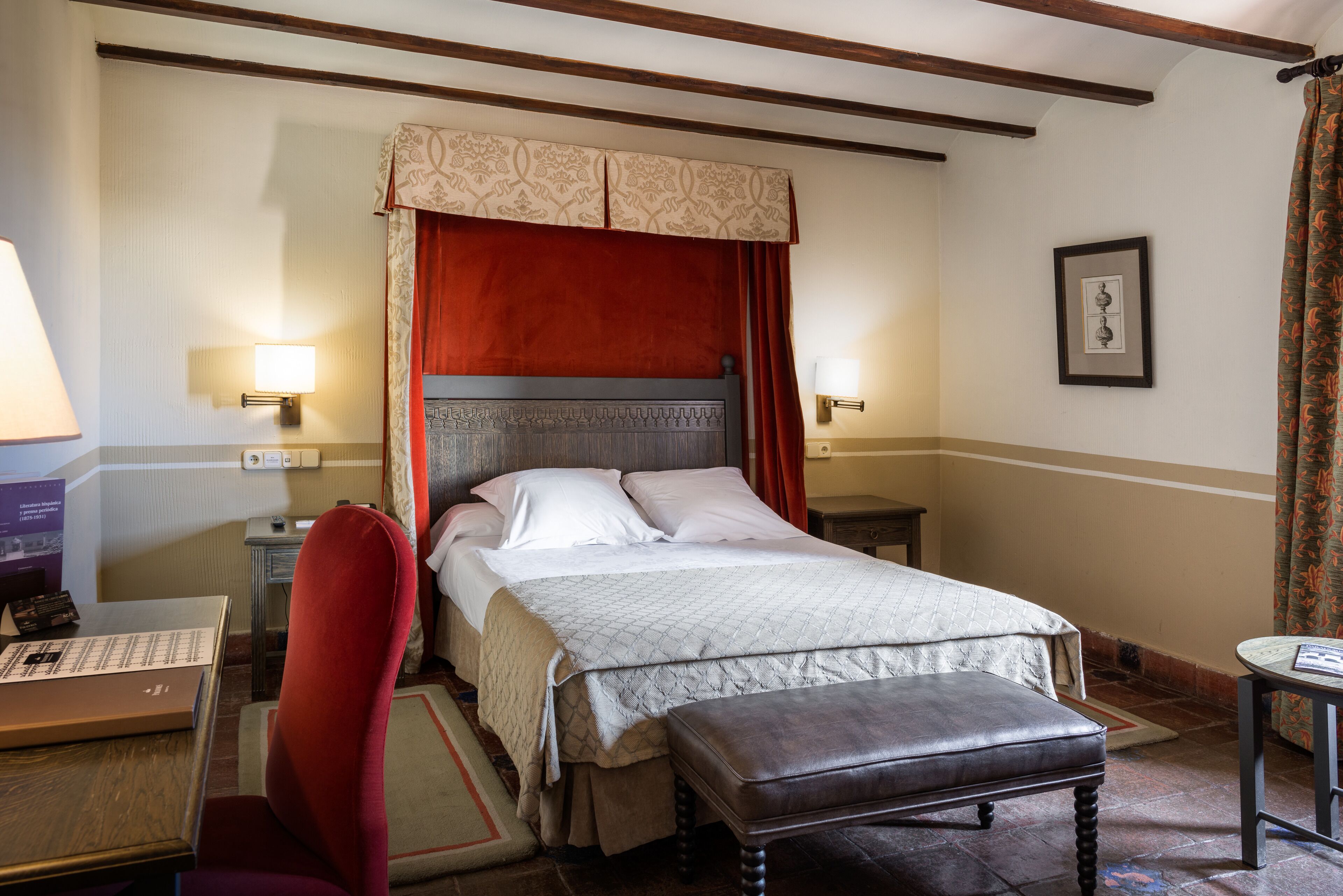 Une chambre d’hôtel avec un lit, un bureau, une chaise, une table et une lampe.