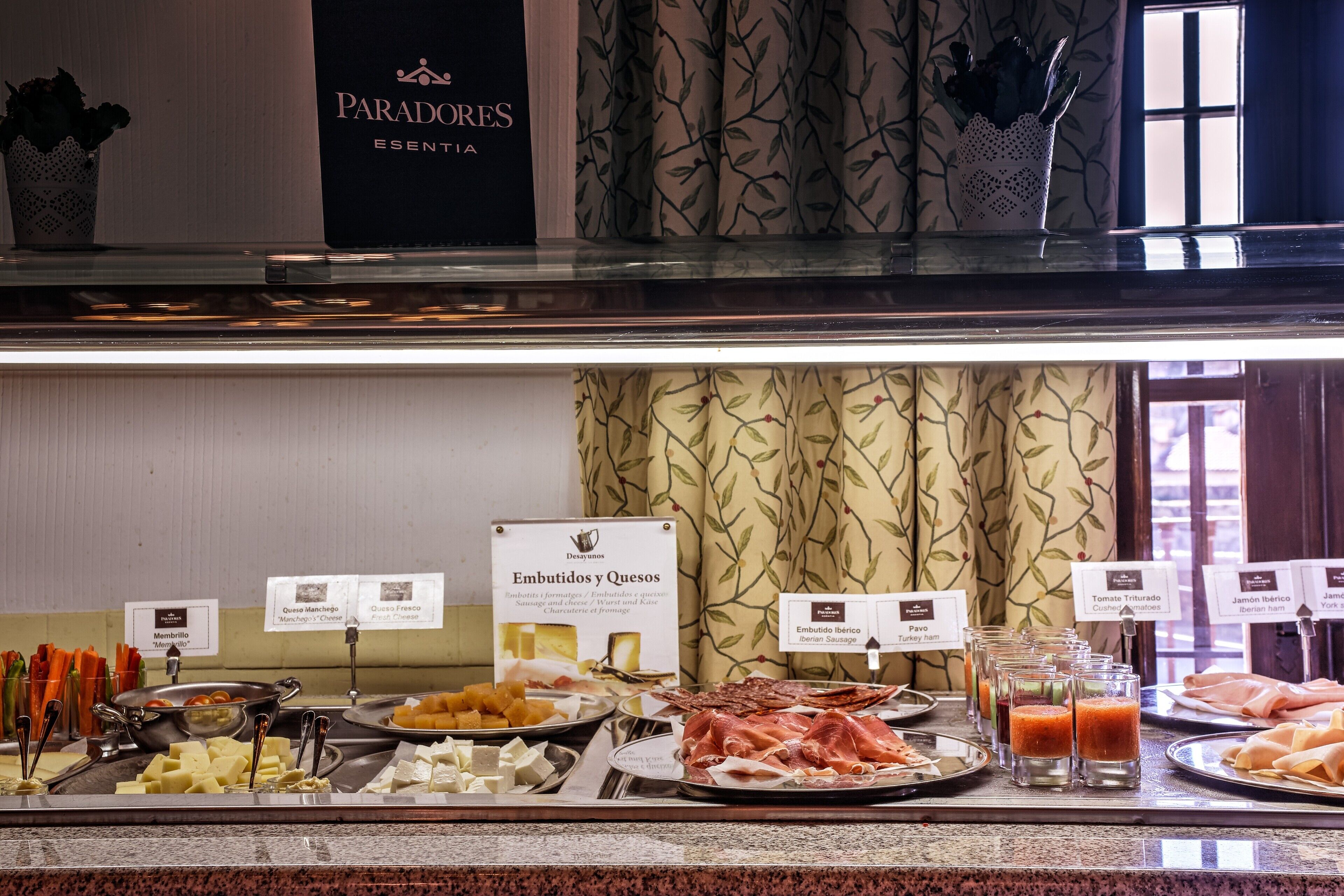 Un bufé con diversas opciones de comida, incluyendo carnes, quesos y jugos.