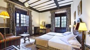 A traditional room with a large bed, a wooden desk, a chair, and a television. - Parador De Santillana De Gil Blas (Santillana del Mar)
