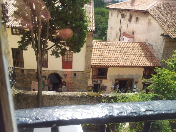 A traditional building with a tiled roof and stone walls, featuring a small shop entrance and a visible staircase.