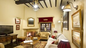 A traditional living room with a fireplace, a television, and classic furniture. - Parador De Santillana De Gil Blas (Santillana del Mar)