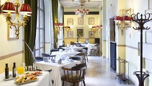 A dining area with tables set for breakfast, including bread, pastries, and beverages. - Parador De Santillana De Gil Blas (Santillana del Mar)