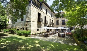 A courtyard with stone buildings, outdoor seating, and greenery.