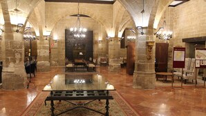 A spacious lobby with a central glass table, stone walls, and chandeliers. - Parador de Santo Domingo de la Calzada (Santo Domingo de la Calzada)