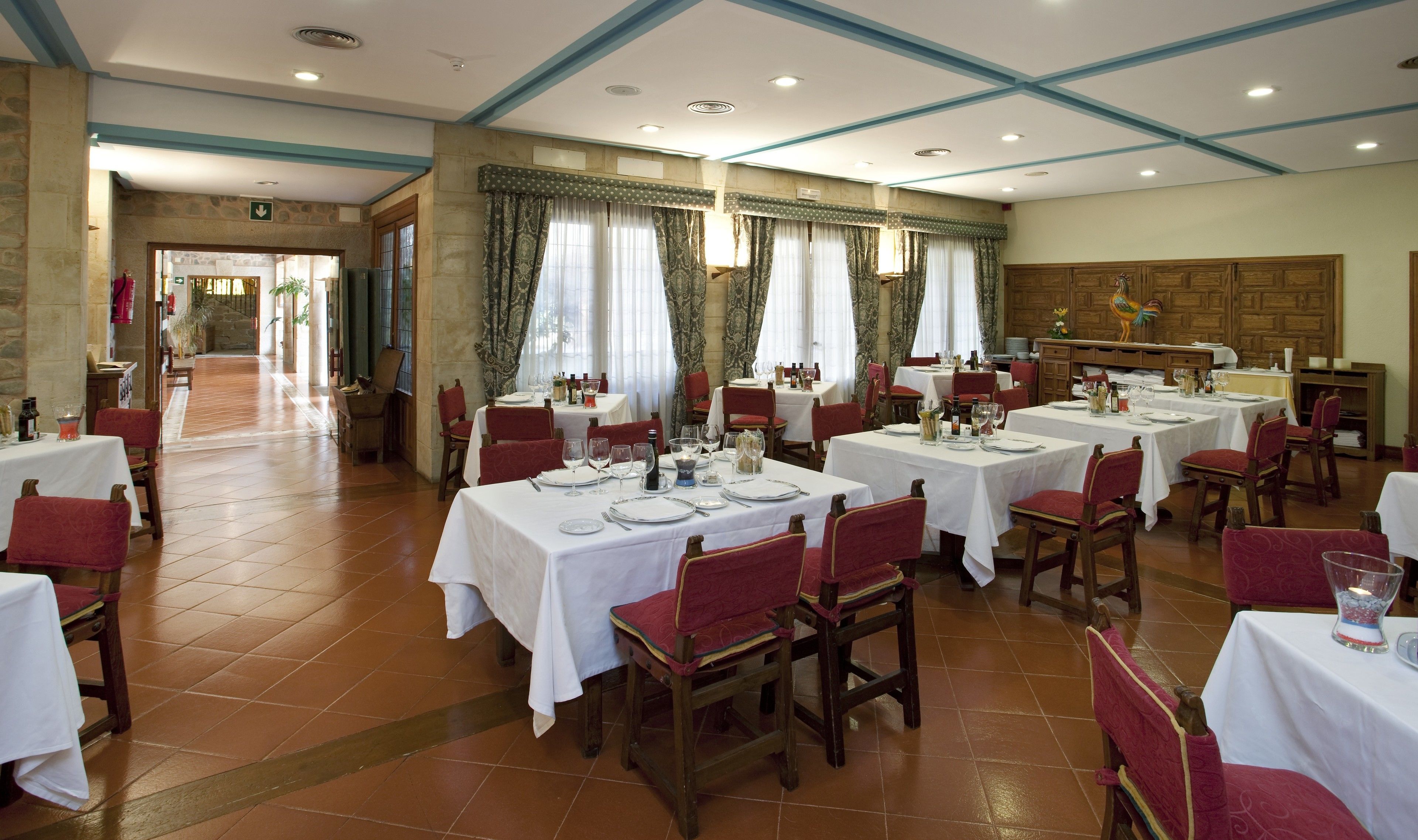 A dining area with multiple tables and chairs, a stone wall, and a wooden cabinet.
