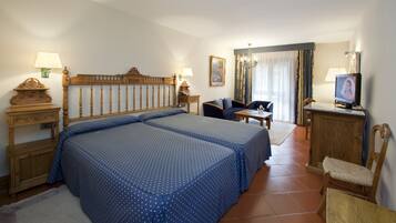 A hotel room with a large bed, two bedside tables, a desk, a chair, and a television.