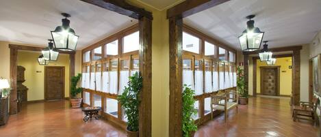 Un hall amplio con vigas de madera, ventanas grandes y plantas en macetas.