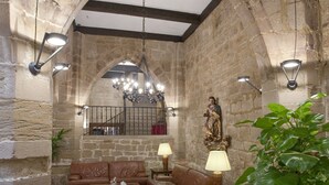 A stone-walled interior with a wooden bench, a table, and a potted plant. - Parador de Santo Domingo de la Calzada (Santo Domingo de la Calzada)