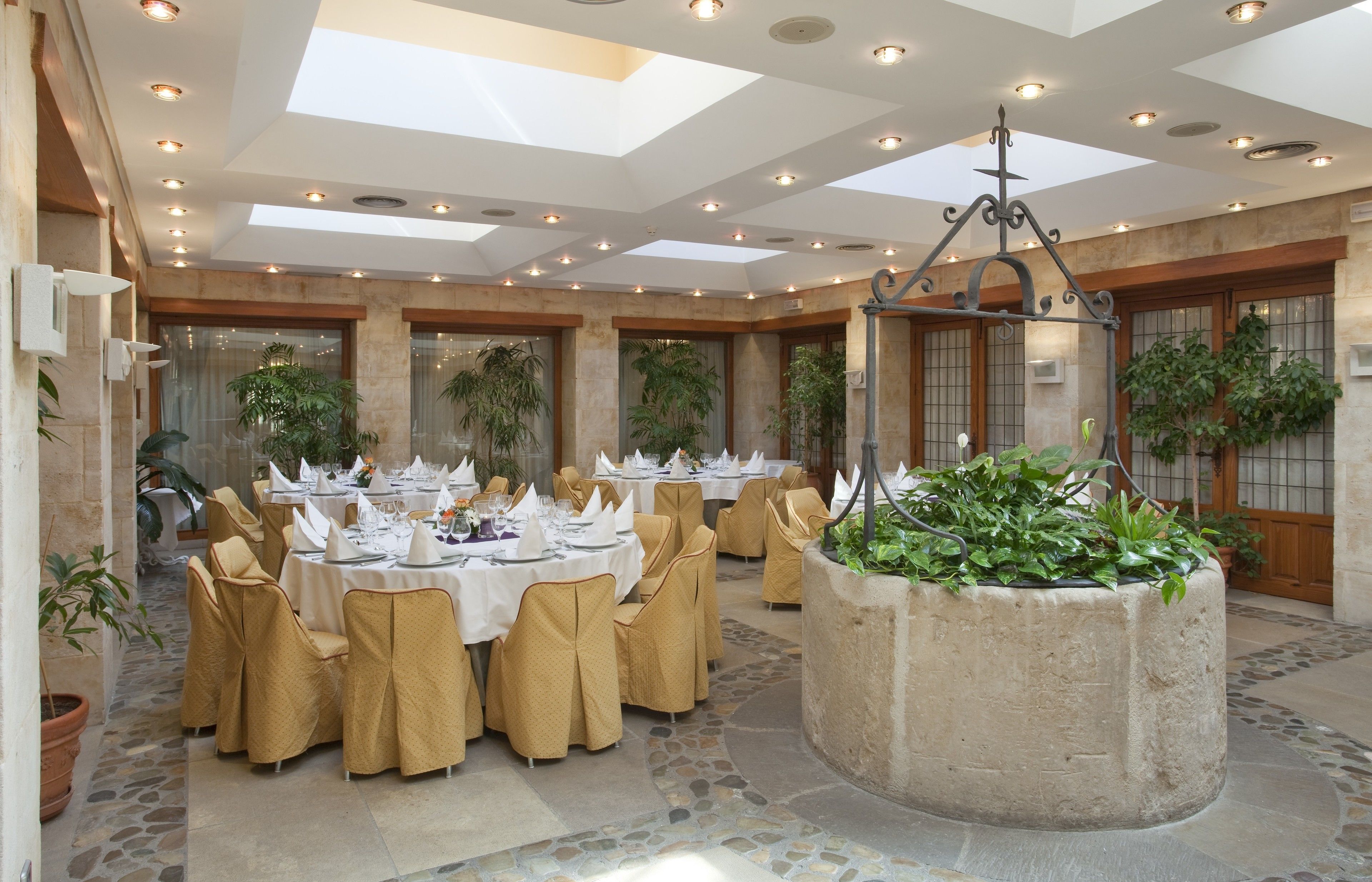 Una sala de banquets amb taules rodones preparades per dinar, envoltades de caires.