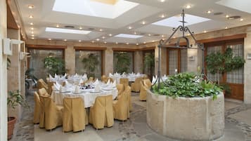 A banquet hall with round tables set for dining, surrounded by chairs.