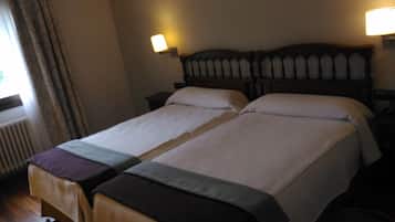 A double bed with a wooden headboard, two bedside tables, and a window with curtains.