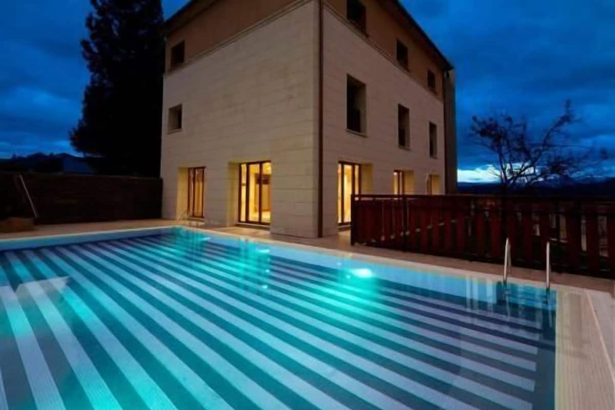A swimming pool with a striped pattern, a building with multiple windows, and a dark sky.