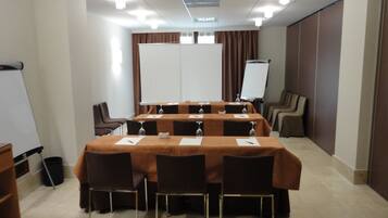 A conference room with a long table, chairs, a whiteboard, and a projector screen.