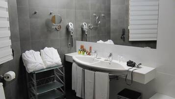 A modern bathroom with a large sink, mirror, and towel rack.