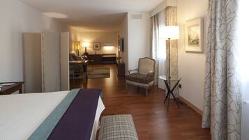 A hotel room with a bed, a chair, a small table, and a sofa.