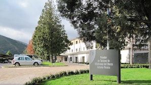 A sign for 'Parador de Turismo de Villafranca del Bierzo Antonio Pereira' with a parking area and a building in the background.