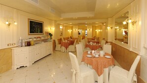 Un comedor amplio con varias mesas y sillas, un mostrador de buffet y un espejo grande en la pared.