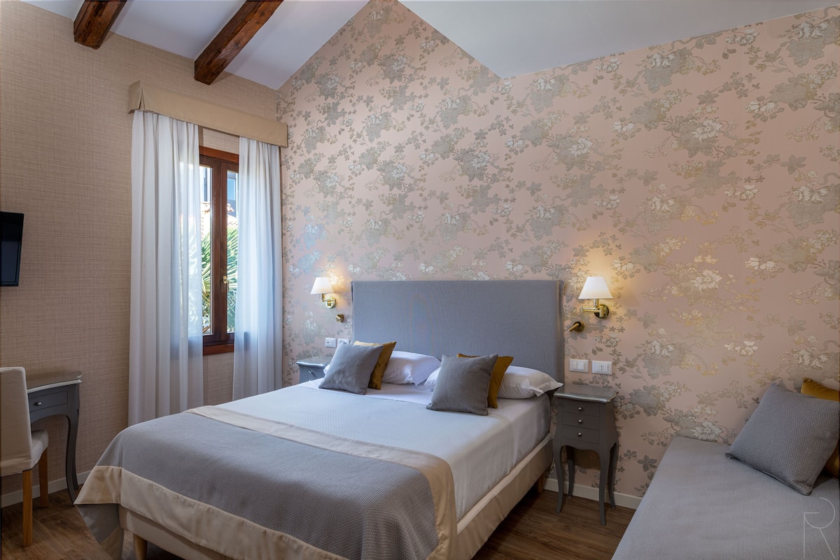 A bedroom with a bed, bedside tables, a desk, and a chair.