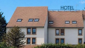 Un hotel con un letrero, varias ventanas y techo de tejas.