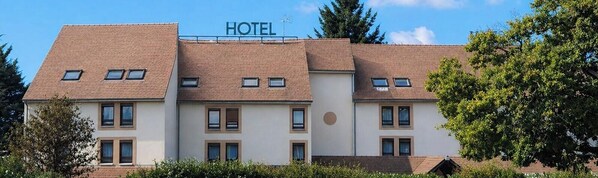Un hôtel avec une enseigne, de nombreuses fenêtres et un toit recouvert de tuiles.