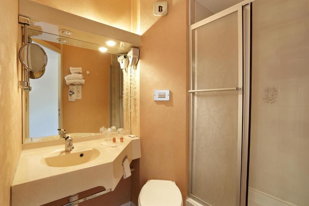 Une salle de bain avec un lavabo, un miroir et des toilettes.